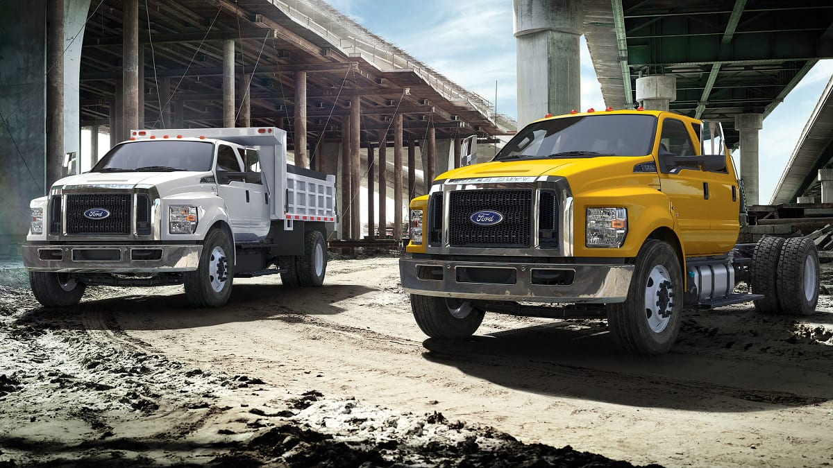 Two Ford F-Series commercial trucks at a construction site.